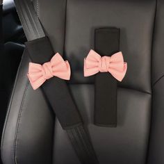 two pink bow ties sitting on the back of a car seat next to a black belt