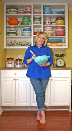 a woman standing in the kitchen holding a bowl