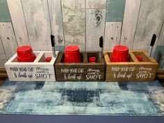 three wooden crates with red cups in them sitting on a blue rug next to a wall