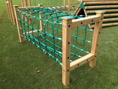 a wooden play structure with green plastic pipes