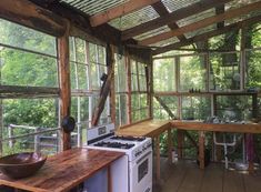 a kitchen with wooden walls and flooring next to a stove top oven under a roof