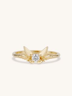 a yellow gold ring with a single diamond in the center and two leaves on each side