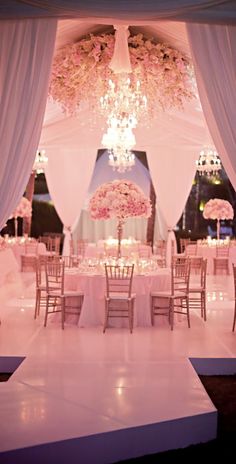 an elegant wedding setup with chandeliers and pink flowers on the ceiling is ready for guests to arrive