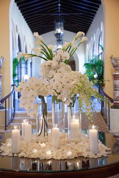 a centerpiece with candles and flowers on a table in front of a staircase way