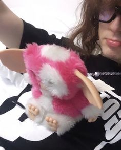 a woman holding a pink and white stuffed animal in her right hand while wearing glasses