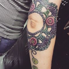 a woman's arm with a tattoo on it that has circles and flowers all over it