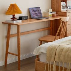 a laptop computer sitting on top of a wooden desk next to a lamp and chair