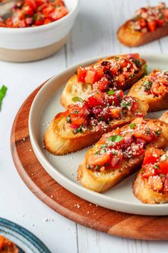 several pieces of bread on a plate with tomatoes and parmesan sprinkles