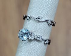 two rings on top of each other sitting on a napkin ring holder with an aqua blue stone in the middle