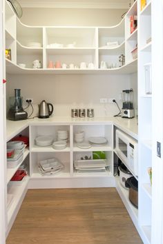 a kitchen with white cabinets and shelves filled with plates, bowls, cups and other items