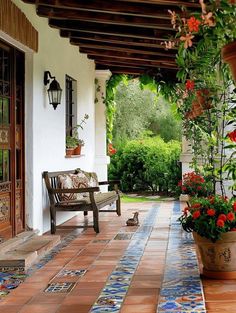 a bench sitting on the side of a building next to potted plants and flowers