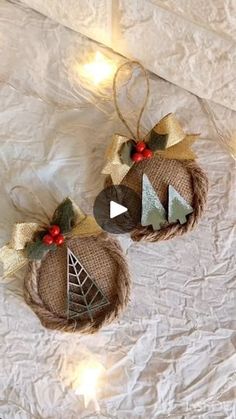 two christmas ornaments hanging from twine with lights