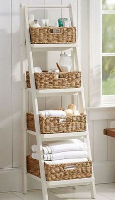 a white ladder shelf with baskets and towels on it