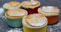 four different colored cupcakes with powdered sugar on top sitting on a counter