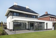 a modern house with solar panels on the roof and glass doors in front of it