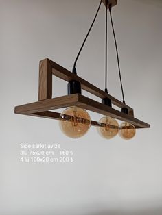 three light fixtures hanging from a wooden beam in a room with white walls and flooring