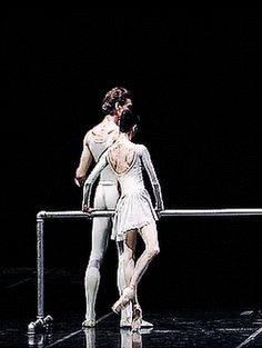 two ballerinas in white tutus standing next to each other on a stage