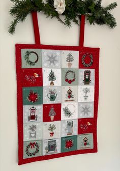 a red bag hanging on the wall with christmas decorations and wreaths attached to it