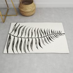 a black and white fern leaf rug on the floor next to a basket with a plant in it