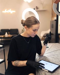 a woman sitting at a table with a tablet in her hand and tattoos on her arm