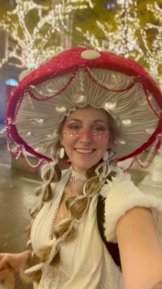 a woman wearing a red and white hat in front of a tree with christmas lights