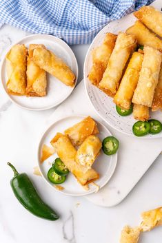 three plates filled with fried food on top of a table next to green peppers and jalapenos