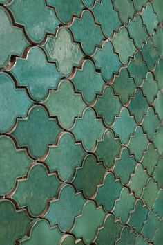 a close up view of an intricately designed green tile wall with metal grates