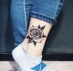 a woman's foot with a rose tattoo on it