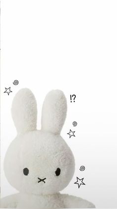 a white stuffed rabbit sitting next to a wall with stars on it's side