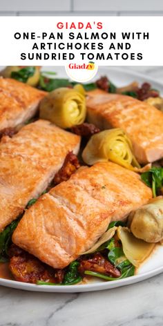 a white plate topped with salmon and artichokes on top of a marble table