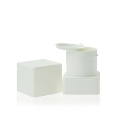 a white container sitting on top of a table next to a small square box with a spoon in it