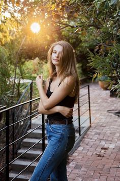 a beautiful young woman standing on top of a brick walkway next to a metal hand rail