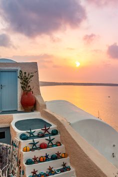 the sun is setting over an oceanfront building with decorative items on it's balcony