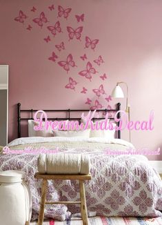 a bedroom with pink butterflies painted on the wall and bed in the foreground is a stool