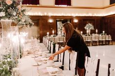 a woman is setting the table for a formal dinner