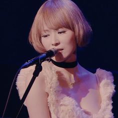 a woman in a white dress singing into a microphone