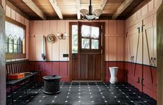 a room with red walls and black flooring has a bench in front of the door