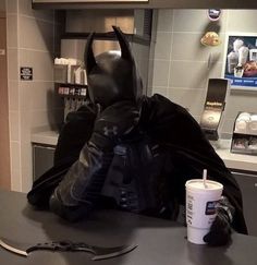 a batman costume sitting on top of a kitchen counter next to a cup of coffee