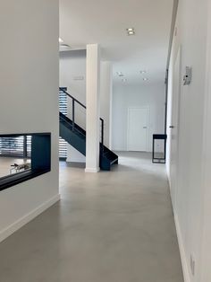 an empty hallway with white walls and stairs