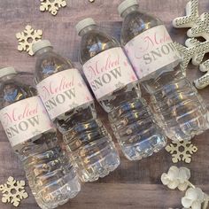 four bottled water bottles sitting on top of a wooden table next to snowflakes