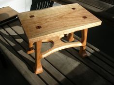 a wooden bench sitting on top of a wooden floor next to a black plastic chair