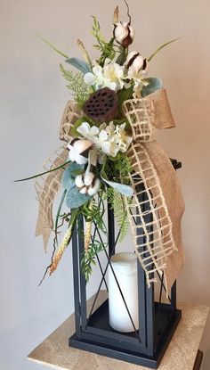 a candle and some flowers are on a table with a burlap ribbon around it