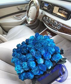 a bouquet of blue roses sits in the center console of a car