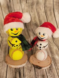 two snowmen with hats and scarfs on top of a wooden table next to each other