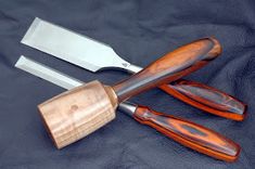 three different types of knifes on a black cloth with wood handles and wooden blades