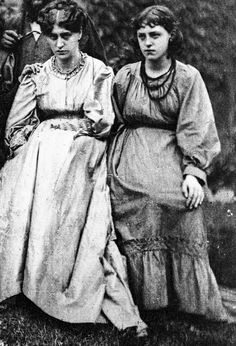 an old black and white photo of two women in dresses standing next to each other