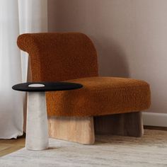 an orange chair sitting on top of a wooden table next to a white rug and window