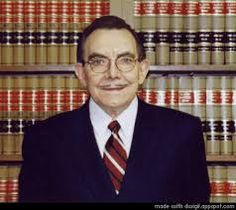 a man in a suit and tie standing in front of a bookshelf filled with law books