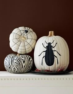 three pumpkins with designs painted on them sitting on a shelf next to each other