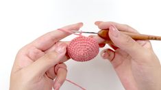 two hands crocheting a ball of yarn with a pair of knitting needles, on a white background